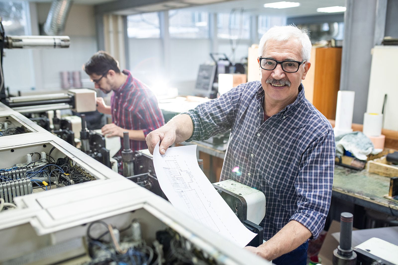man-getting-printed-paper-out-of-printing-press-min